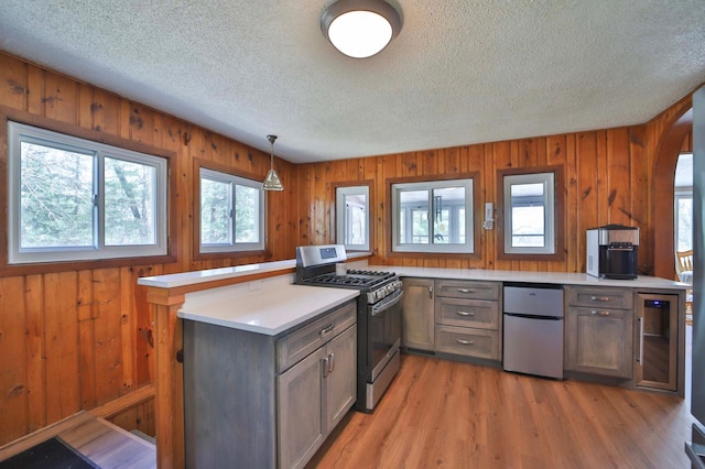 kitchen with stainless steel gas range oven, fridge, a textured ceiling, light countertops, and wine cooler