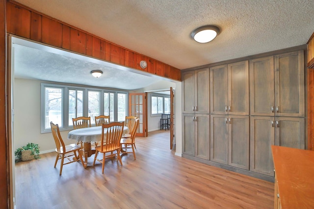 dining room with a textured ceiling, baseboards, and light wood-style floors