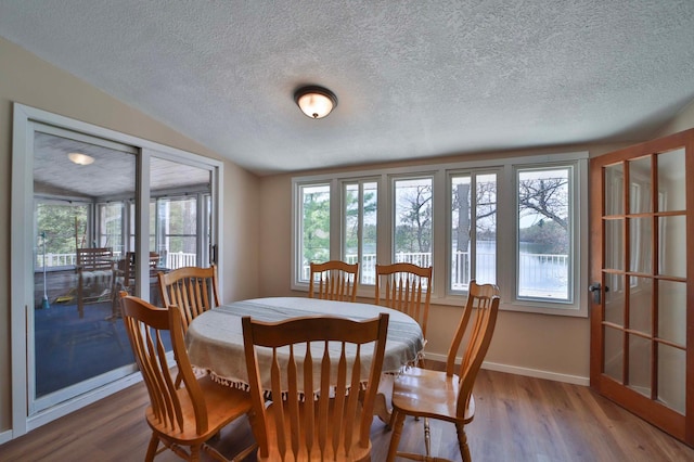 dining area featuring baseboards, a textured ceiling, and wood finished floors