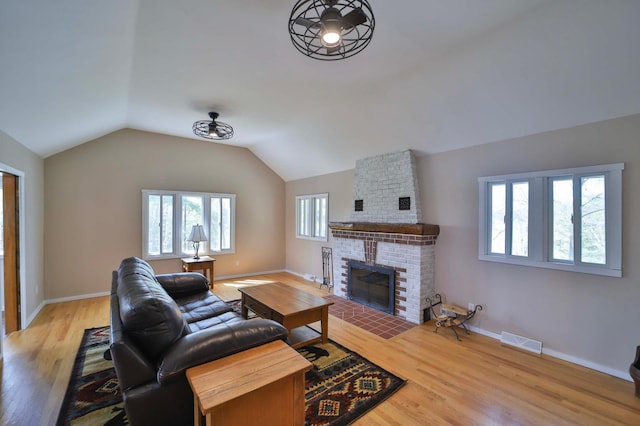 living area featuring a fireplace, wood finished floors, baseboards, and vaulted ceiling