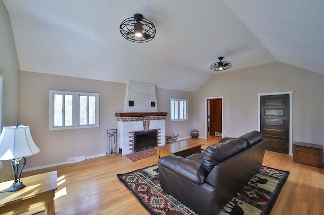 living area with lofted ceiling, wood finished floors, a fireplace, and baseboards