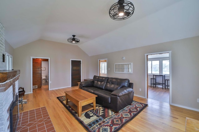 living room with wood finished floors, lofted ceiling, a fireplace, and healthy amount of natural light