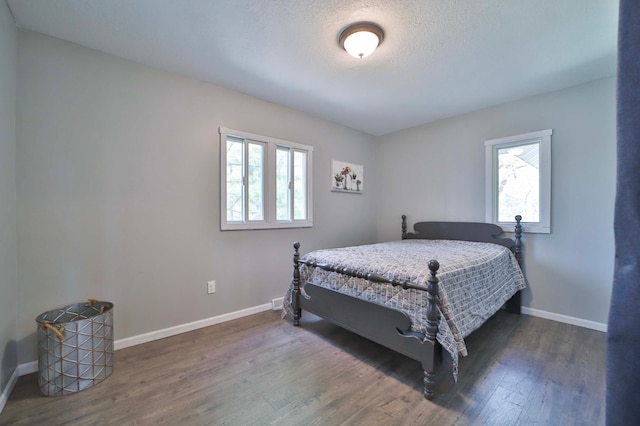 bedroom with multiple windows, wood finished floors, and baseboards