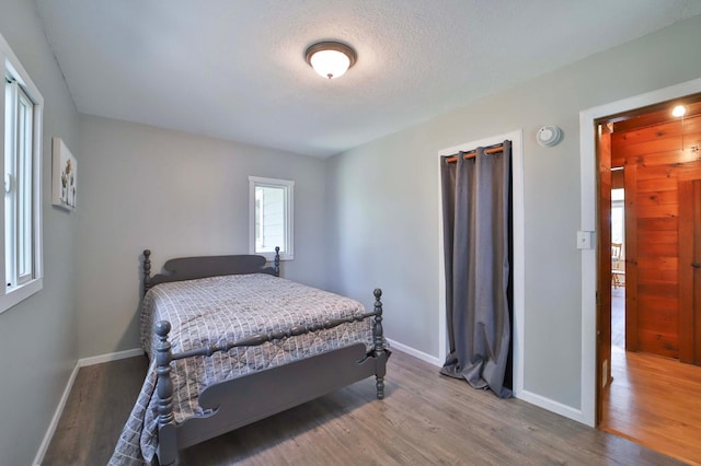 bedroom featuring wood finished floors, baseboards, and a textured ceiling