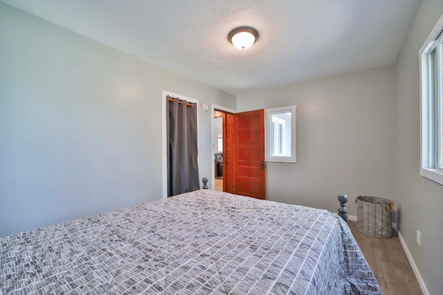 bedroom with wood finished floors, baseboards, and a textured ceiling