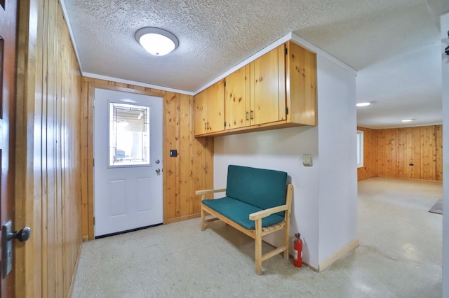 entrance foyer featuring wooden walls, baseboards, and a textured ceiling