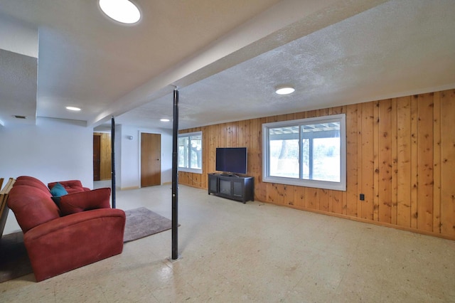 living room featuring tile patterned floors, wooden walls, baseboards, and recessed lighting