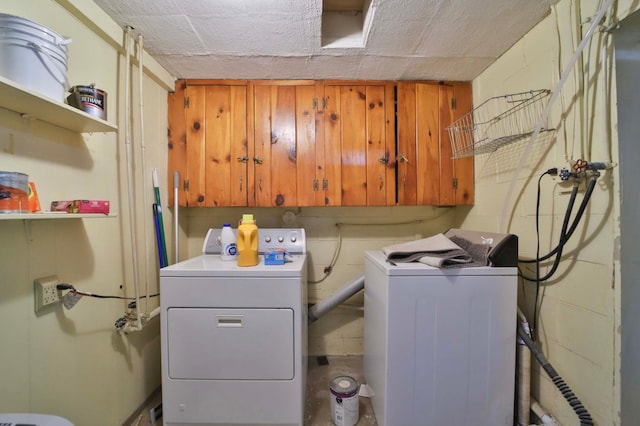 laundry room featuring independent washer and dryer, cabinet space, and concrete block wall