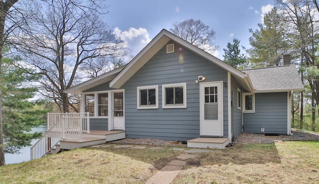 rear view of property with a shingled roof, a deck, a chimney, a lawn, and a sunroom