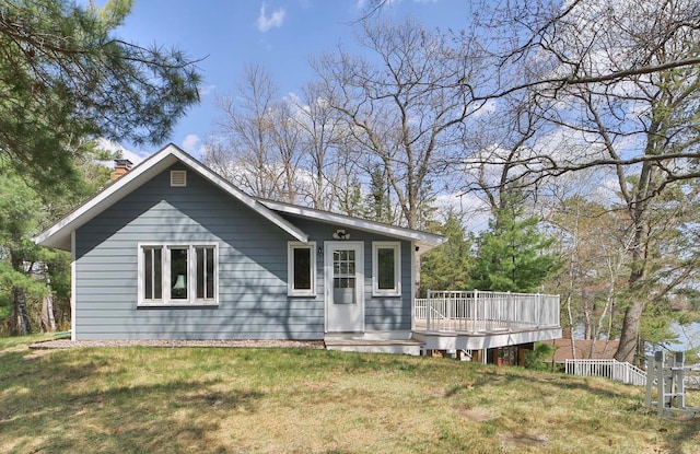 view of front of home featuring a chimney, a deck, and a front yard
