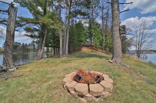 view of green lawn featuring an outdoor fire pit and a water view