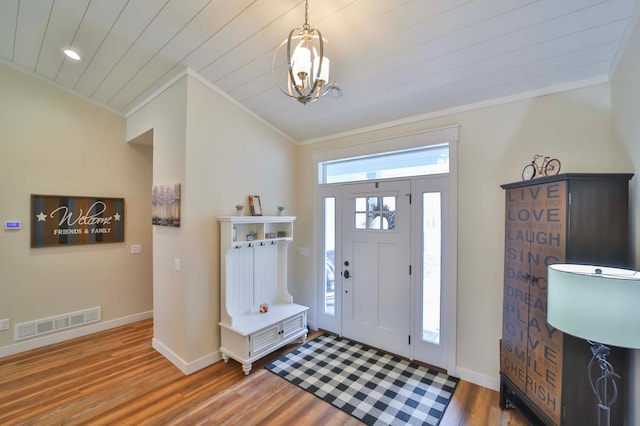 foyer entrance with crown molding, baseboards, wood finished floors, and visible vents