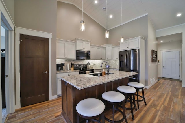 kitchen with dark wood-style flooring, electric range, a sink, stainless steel fridge with ice dispenser, and high vaulted ceiling