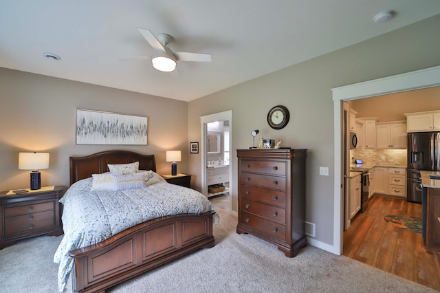 bedroom featuring ensuite bathroom, baseboards, ceiling fan, carpet, and black fridge