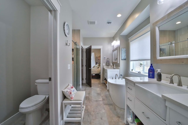 bathroom with a freestanding bath, a sink, toilet, visible vents, and a stall shower