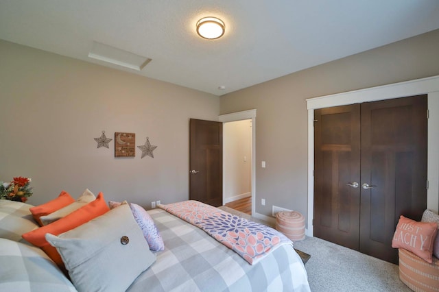 bedroom with a closet, attic access, baseboards, and carpet flooring