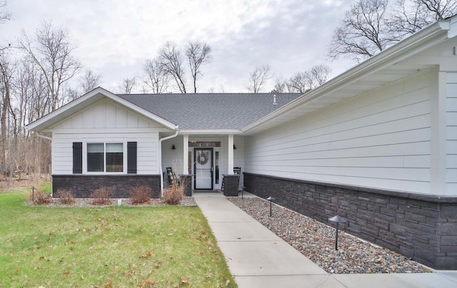 view of front of home with board and batten siding, a porch, stone siding, and a front lawn