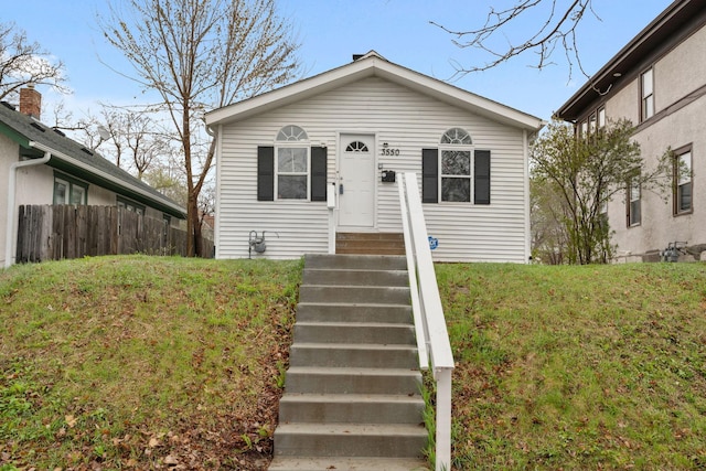 view of front of home with a front lawn, fence, and entry steps