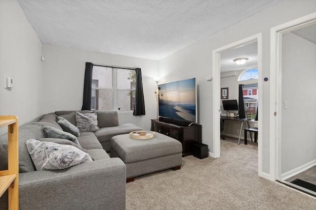 living room with a textured ceiling, light colored carpet, and baseboards