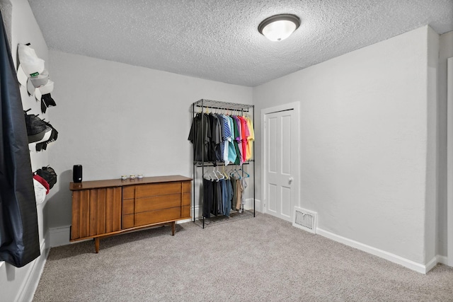 bedroom with visible vents, a textured ceiling, baseboards, and light colored carpet