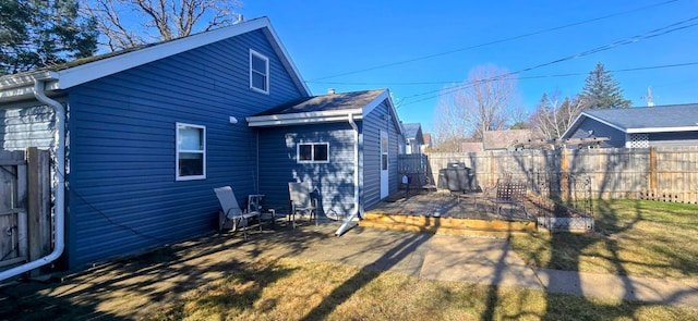 rear view of house featuring a lawn and a fenced backyard