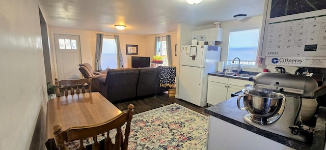 kitchen featuring freestanding refrigerator, a sink, dark countertops, and white cabinetry
