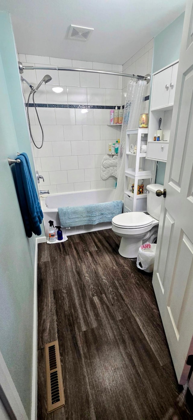 bathroom with tiled shower / bath combo, toilet, visible vents, and wood finished floors
