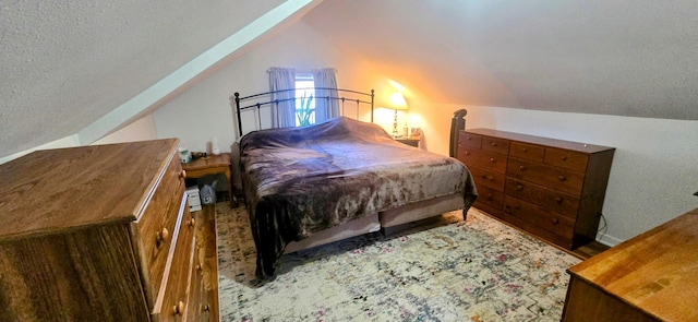 bedroom featuring vaulted ceiling, a textured ceiling, and wood finished floors