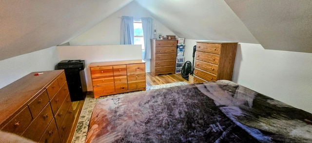 bedroom with light wood-style floors and lofted ceiling