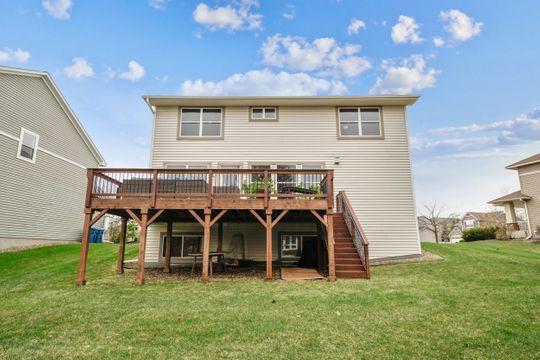back of property with a wooden deck, stairway, and a lawn