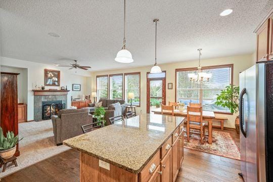 kitchen with freestanding refrigerator, a textured ceiling, plenty of natural light, brown cabinets, and a center island