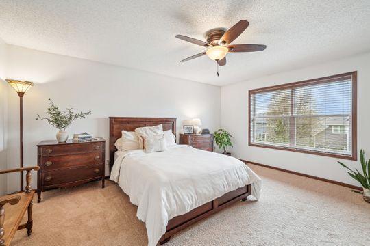 bedroom with light carpet, a textured ceiling, baseboards, and ceiling fan