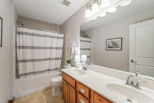 bathroom with toilet, double vanity, and shower / tub combo