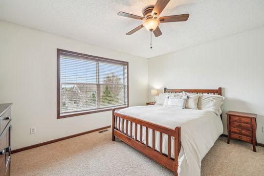 bedroom featuring light colored carpet, a textured ceiling, baseboards, and a ceiling fan