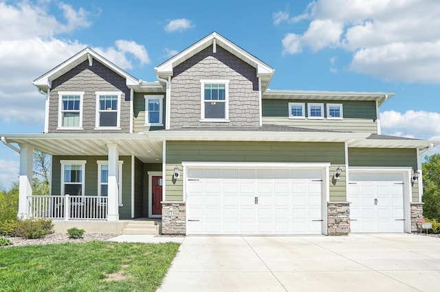 craftsman-style house featuring covered porch, a garage, driveway, and stone siding