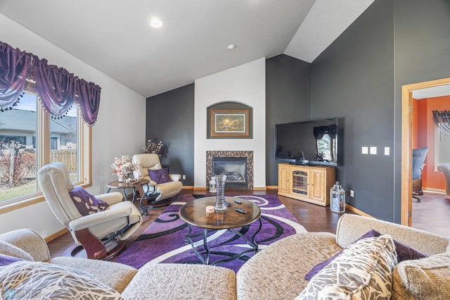 living area with a premium fireplace, baseboards, wood finished floors, and high vaulted ceiling