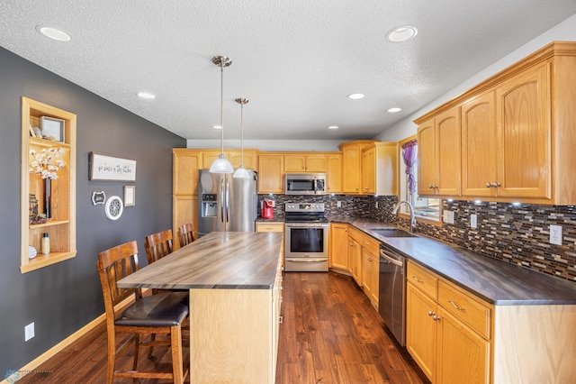 kitchen with dark wood-style flooring, appliances with stainless steel finishes, a sink, a breakfast bar area, and decorative backsplash