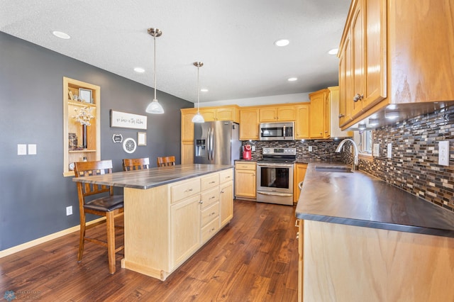 kitchen with a sink, appliances with stainless steel finishes, backsplash, and dark countertops