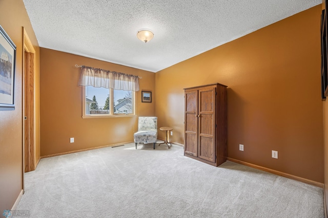 sitting room with carpet floors, a textured ceiling, visible vents, and baseboards