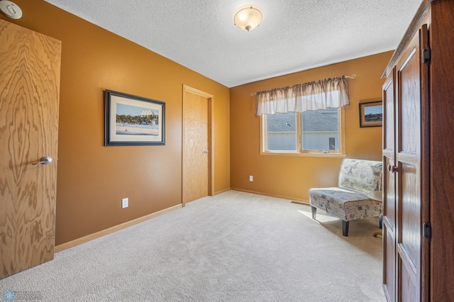sitting room with baseboards, light carpet, and a textured ceiling