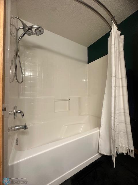 bathroom featuring shower / bath combo and a textured ceiling
