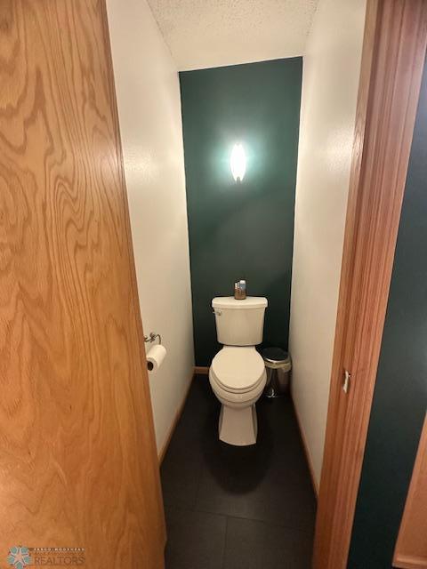 bathroom featuring tile patterned flooring, a textured ceiling, and toilet