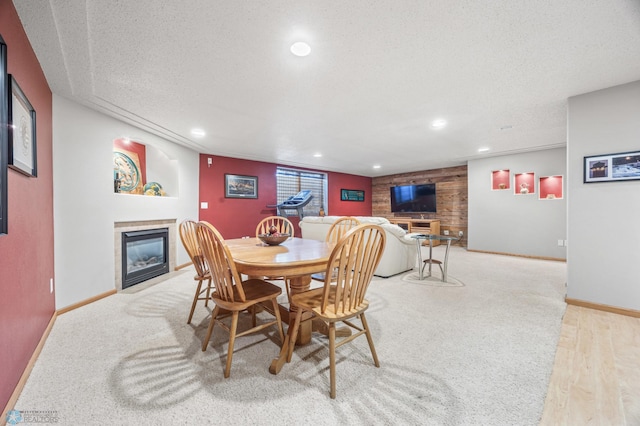 dining space featuring recessed lighting, a textured ceiling, baseboards, and a glass covered fireplace