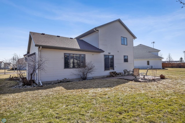 rear view of house with fence, a patio, a lawn, and roof with shingles