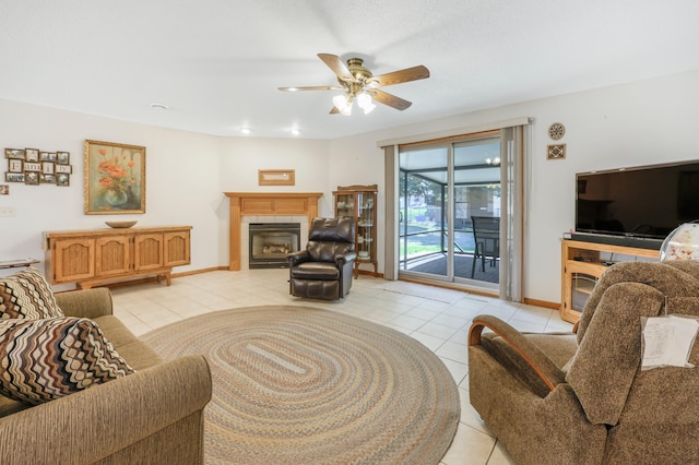 living room featuring a tiled fireplace, baseboards, a ceiling fan, and light tile patterned flooring