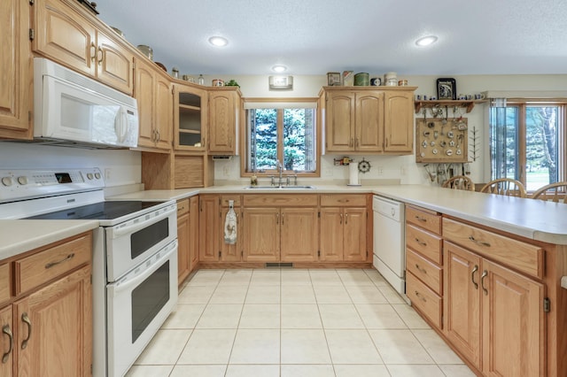kitchen featuring a healthy amount of sunlight, white appliances, a peninsula, and a sink