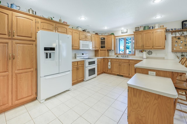 kitchen featuring a sink, light countertops, light tile patterned flooring, white appliances, and a peninsula