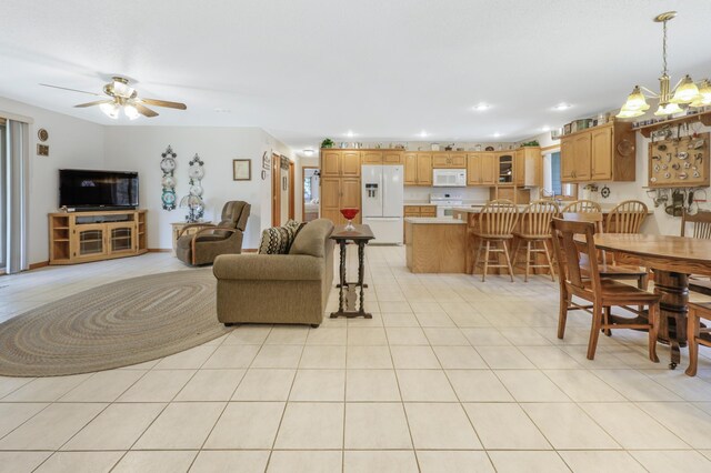 living room featuring light tile patterned floors, recessed lighting, and ceiling fan with notable chandelier