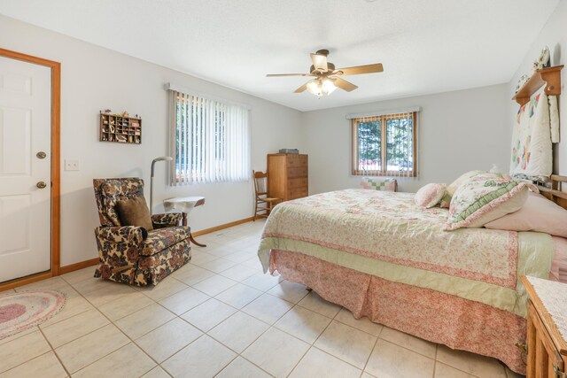 bedroom featuring baseboards, light tile patterned flooring, ceiling fan, and multiple windows