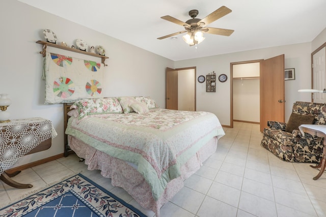tiled bedroom with ceiling fan, a spacious closet, baseboards, and a closet